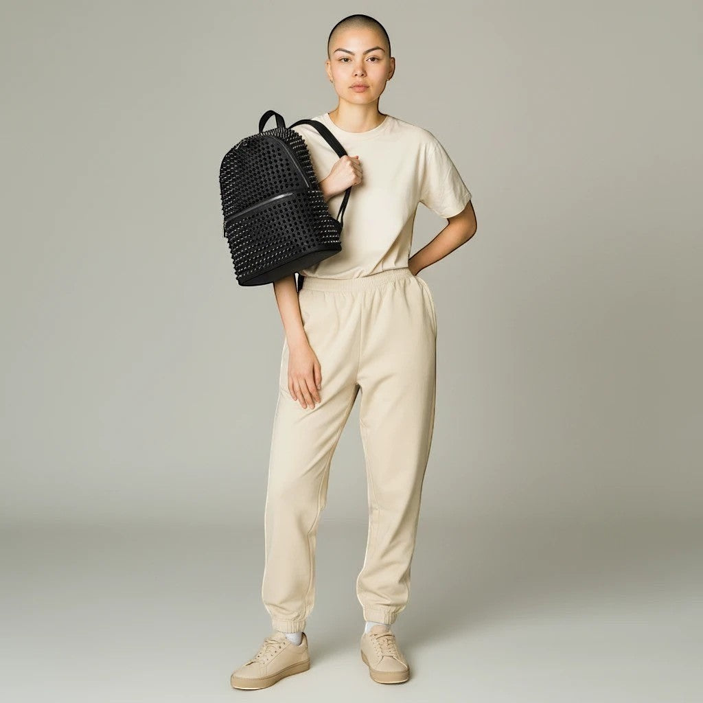 Modelka SchoolKit prezentuje czarny plecak w stylu koreańskim z nitami, zestawiony z beżowym dresem.